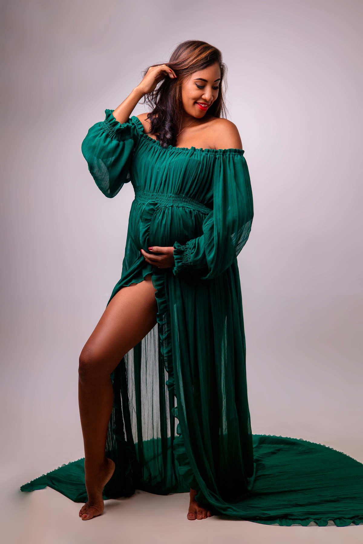 gestante com mão na barriga e outra segurando o cabelo olhando pro ombro