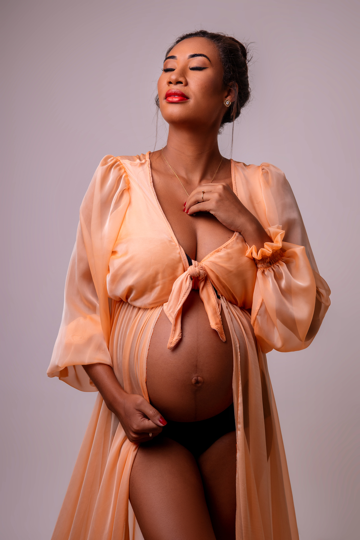 gestante com mão na barriga e outra no colar