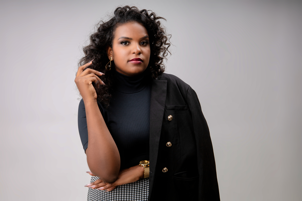 nail designer com blazer no ombro e braço cruzado