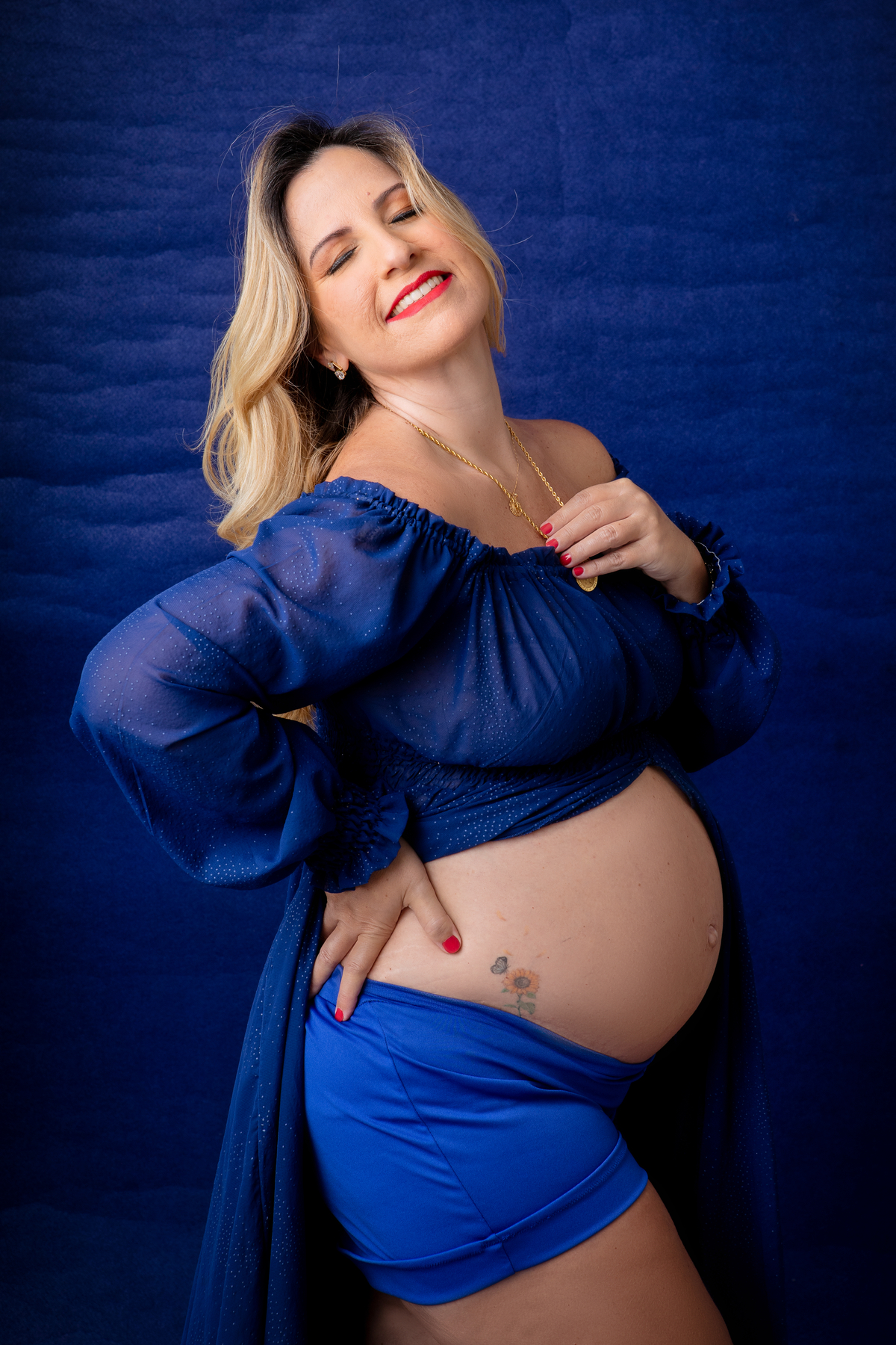 gestante com mão na cintura e outra no colar