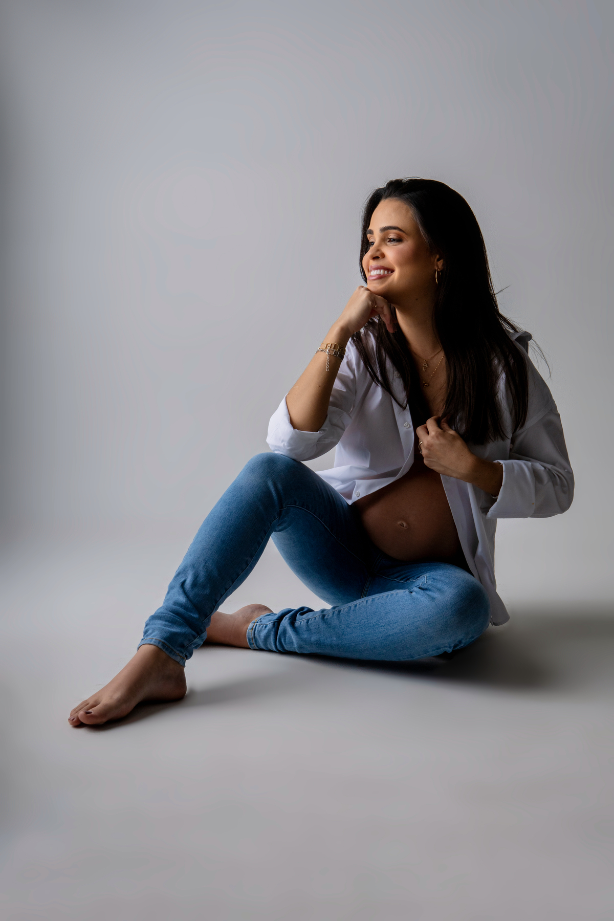 gestante de calça segurando a camisa e braço apoiado