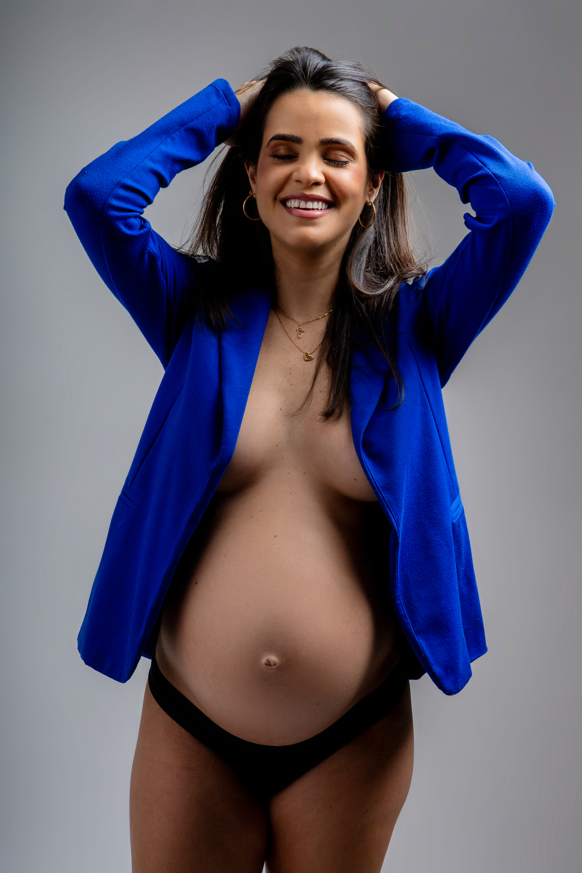 gestante de blazer azul com mãos no cabelo