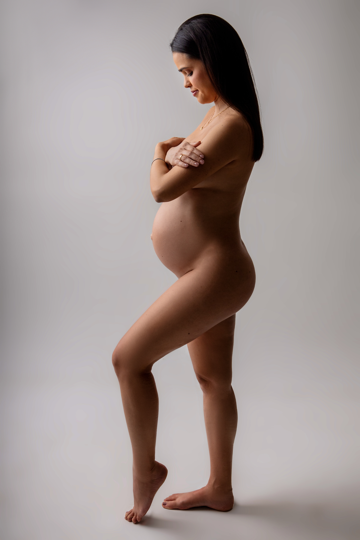gestante nua com braços cruzados no seios