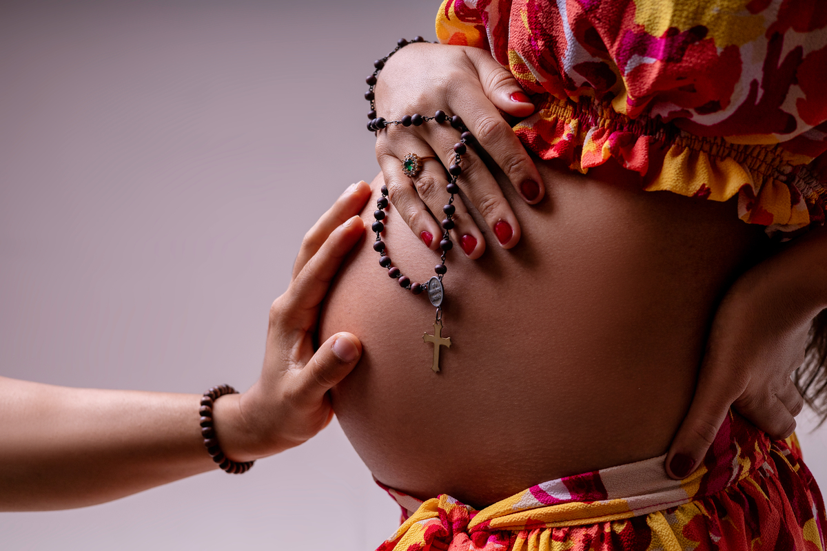 detalhe: mão de papai na barriga da gestante com o terço