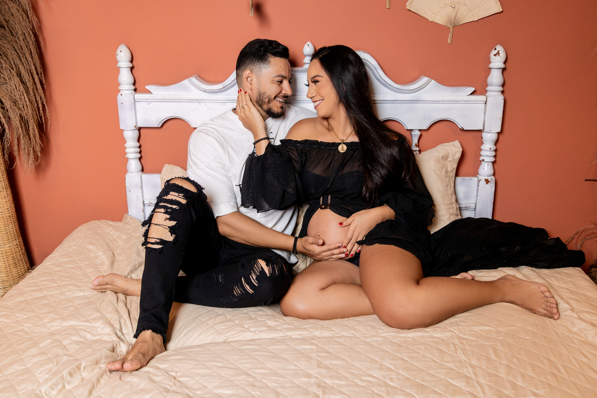 papai e gestante sentados na cama tocando na barriga