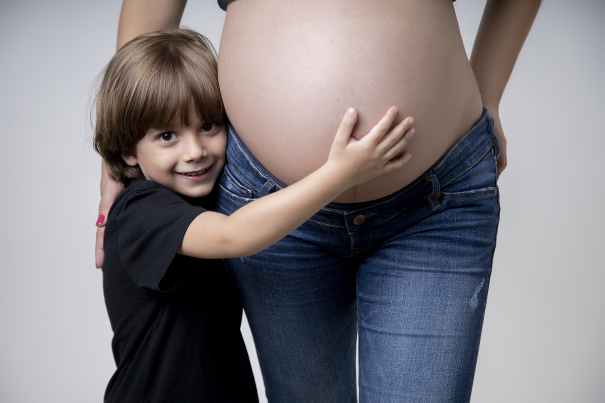 filho abraçando a barriga da gestante
