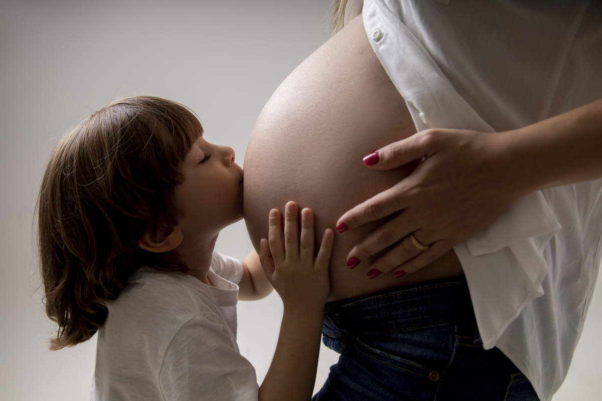 detalhe do filho beijando a barriga da gestante