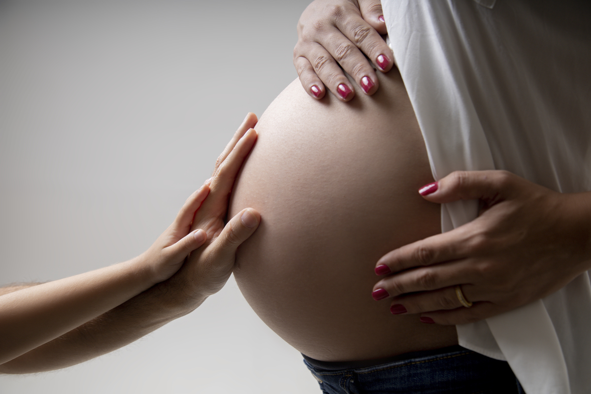 detalhe de mãos de papai e filho tocando na barriga da gestante