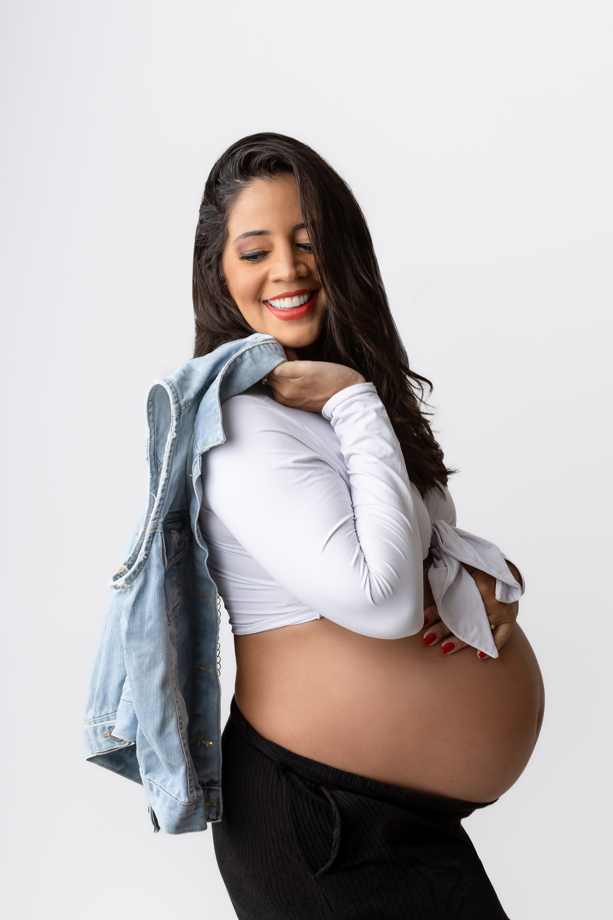 gestante segurando o colete jeans e tocando na barriga