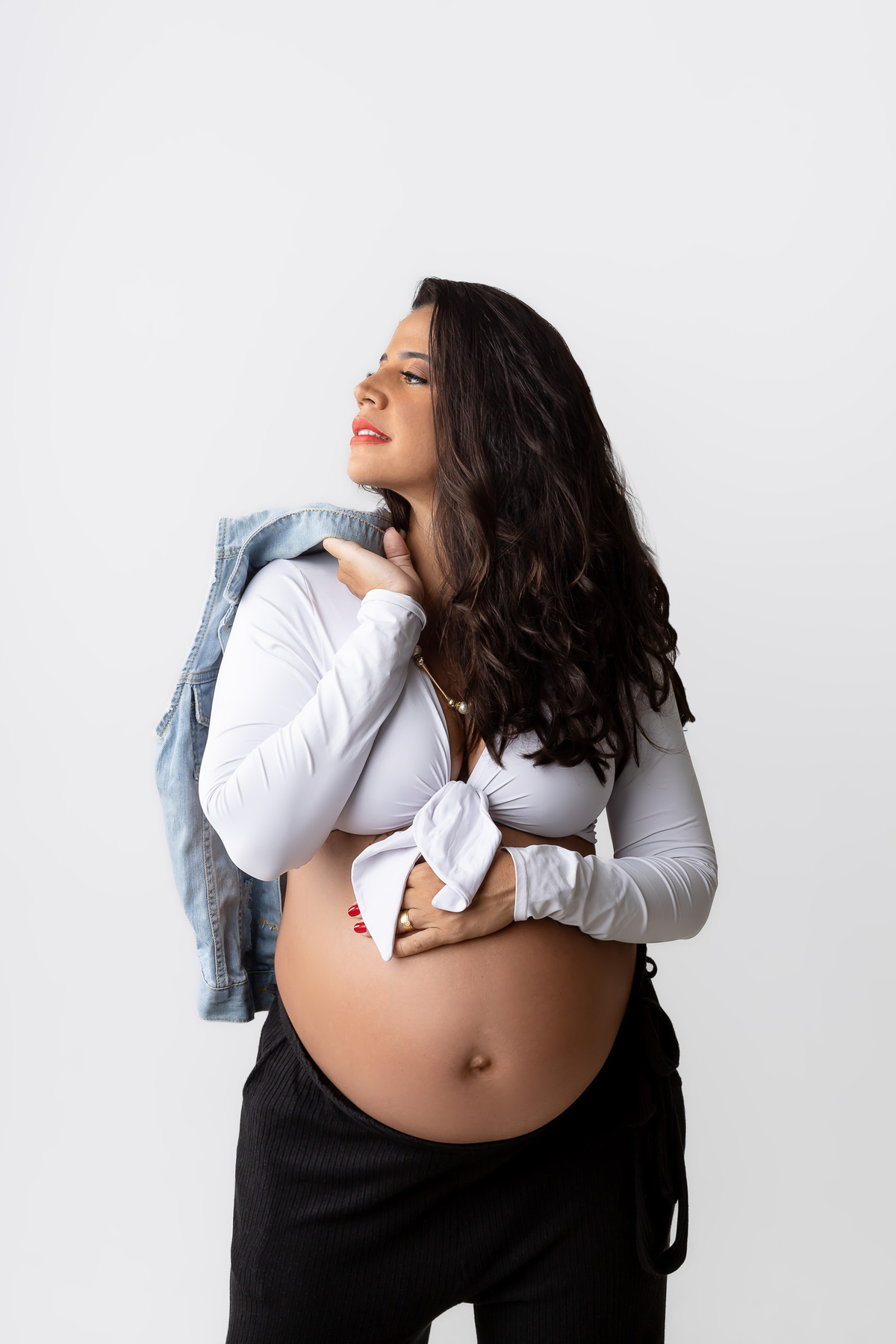 gestante segurando o colete jeans e tocando na barriga