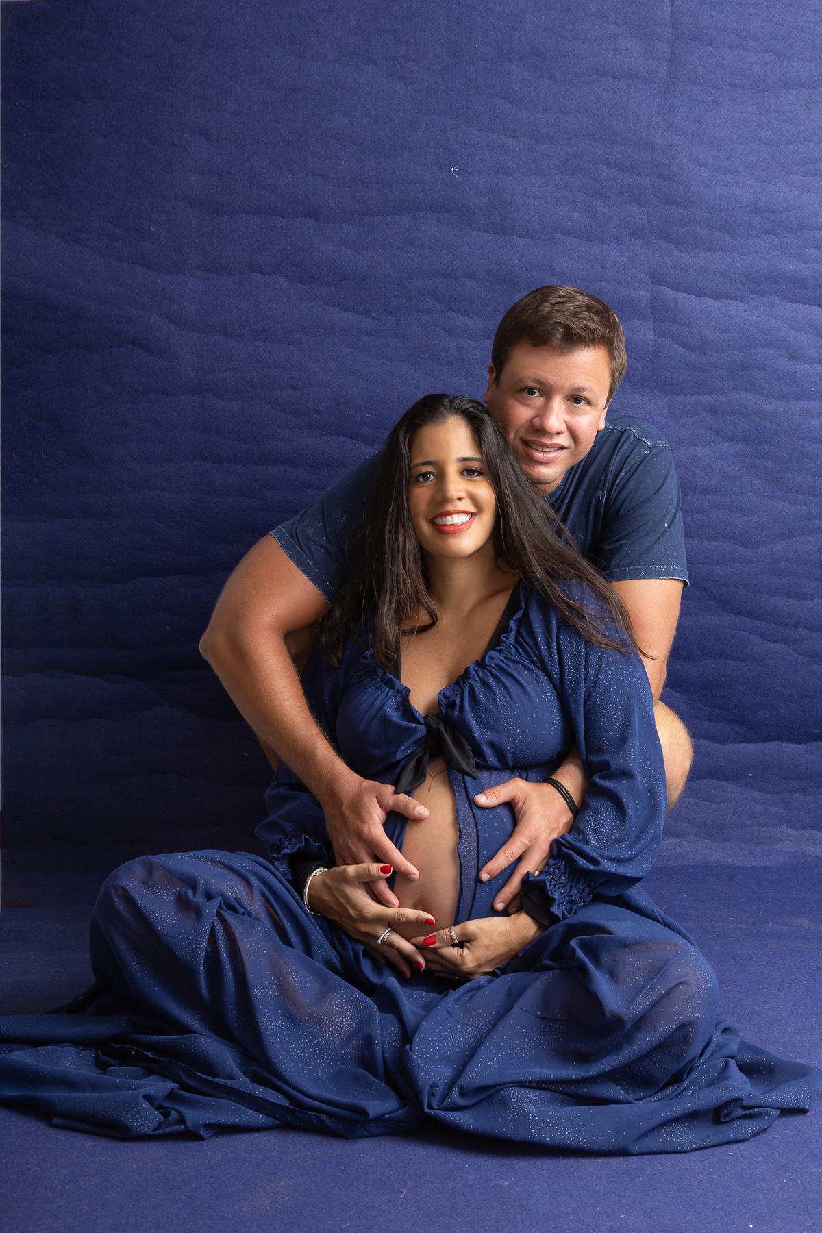 gestante sentada com papai atrás tocando na barriga