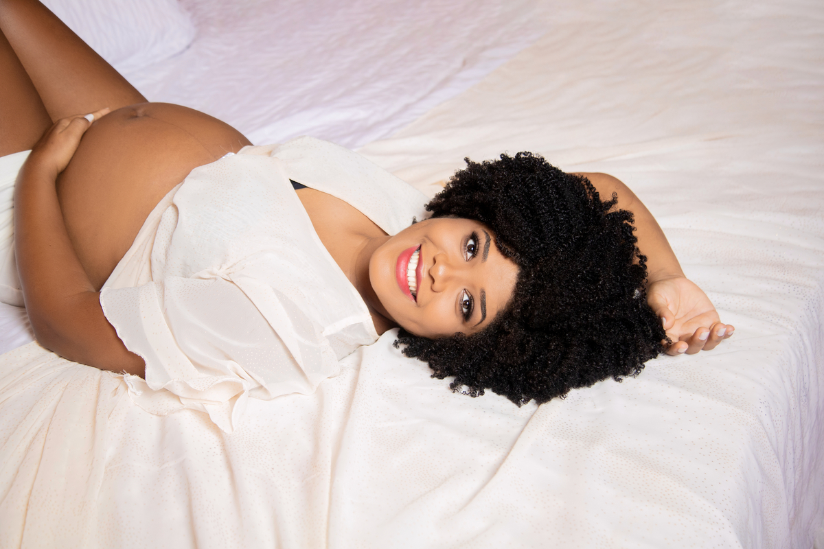 
gestante deitada com mão na barriga e outra sobre a cabeça