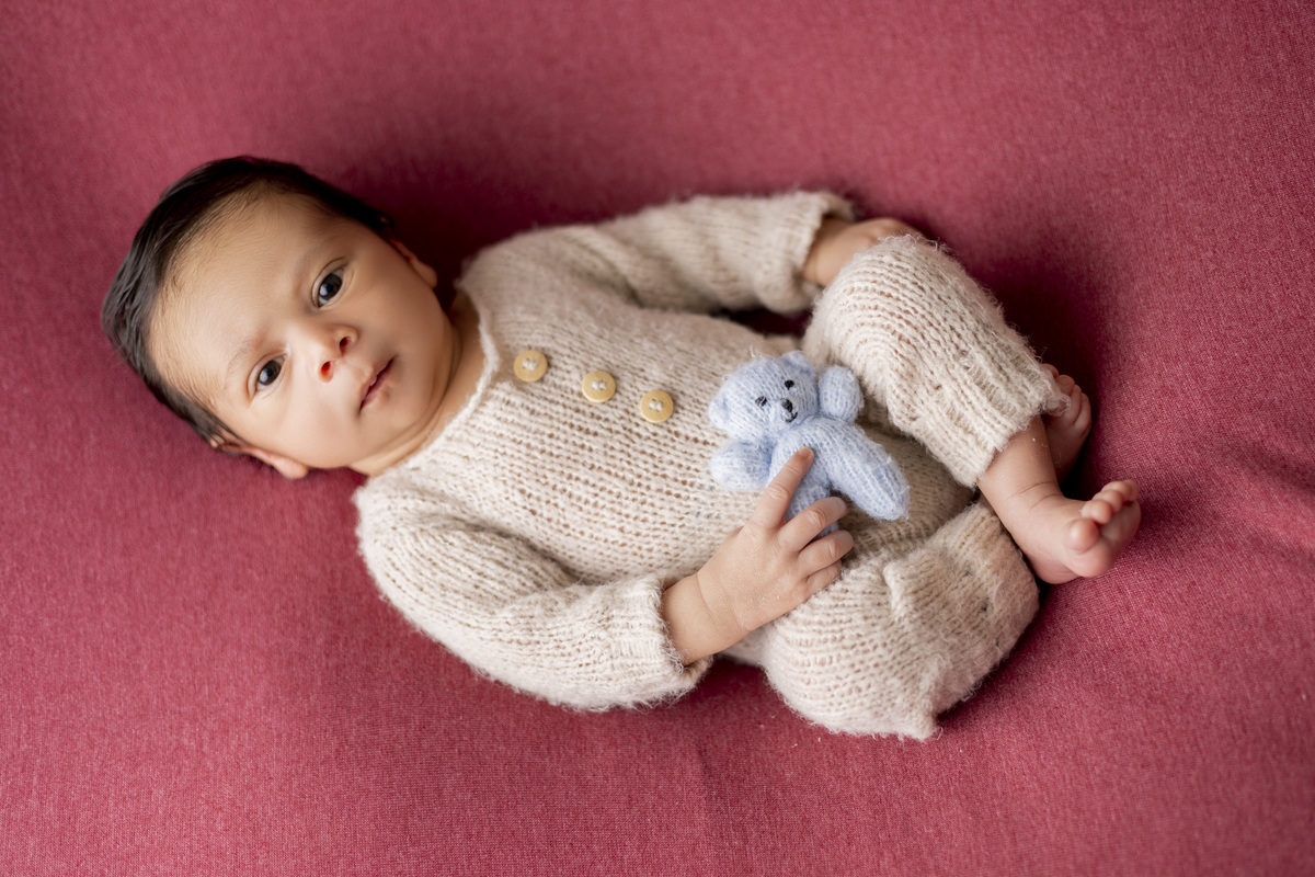 newborn deitado de barriga pra cima com ursinho