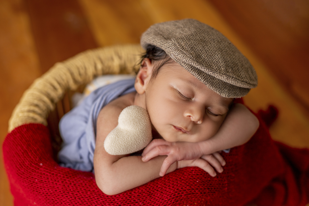 newborn coberto no balde com boina e coração