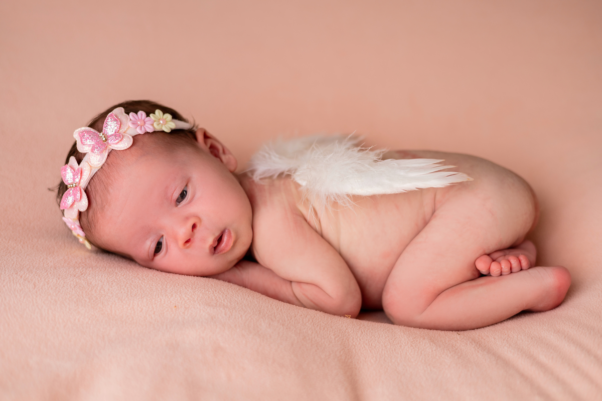 newborn de bruços com asas de anjo