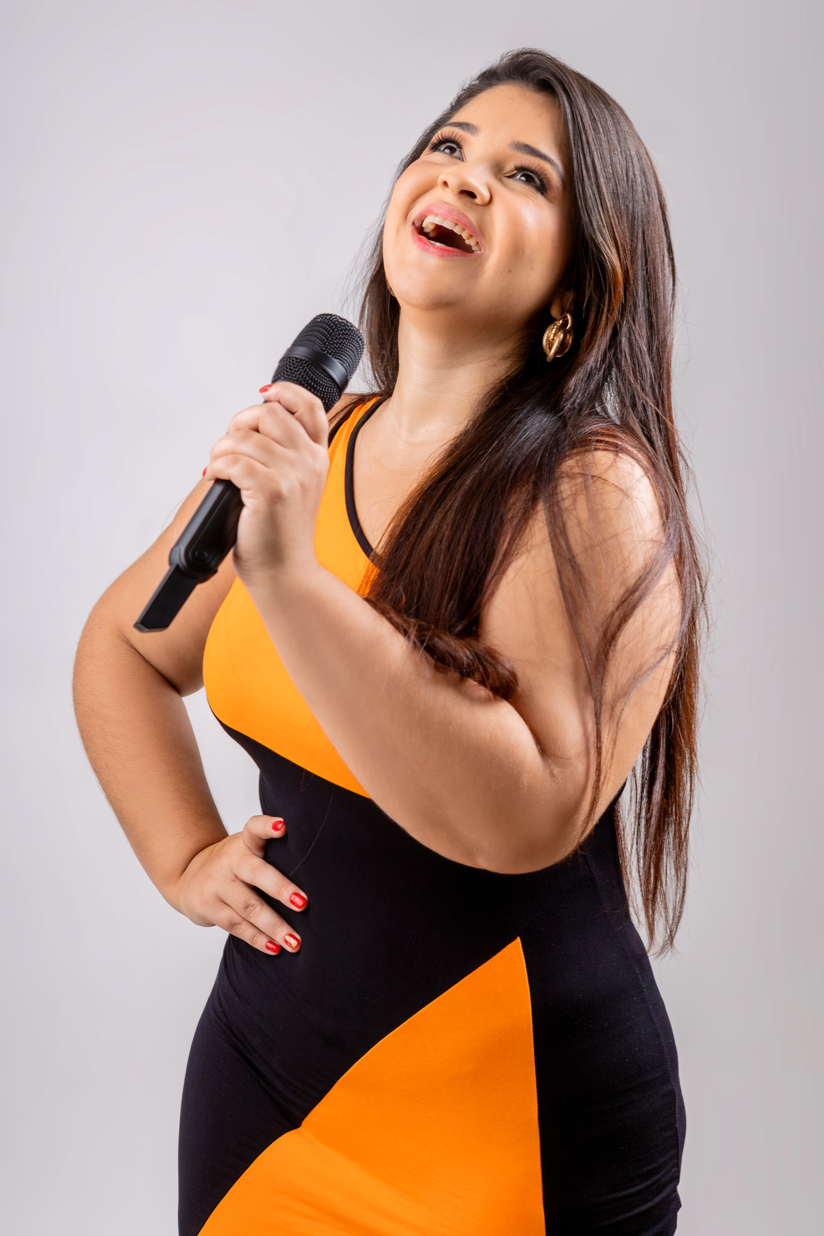 cantora com mão na cintura e segurando o microfone na outra mão
