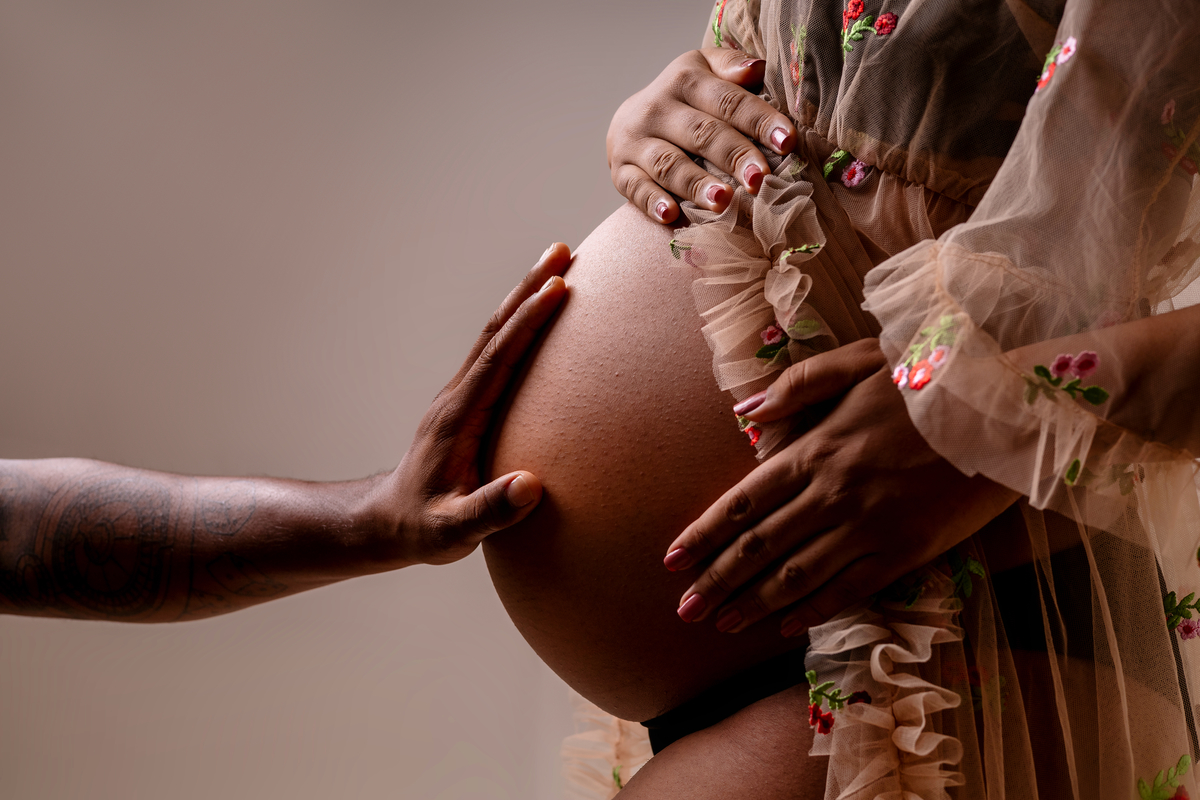 detalhe de mão do papai tocando na barriga da gestante