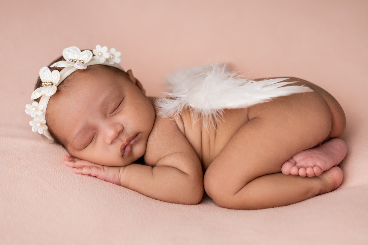 newborn de bruços com asas de anjo