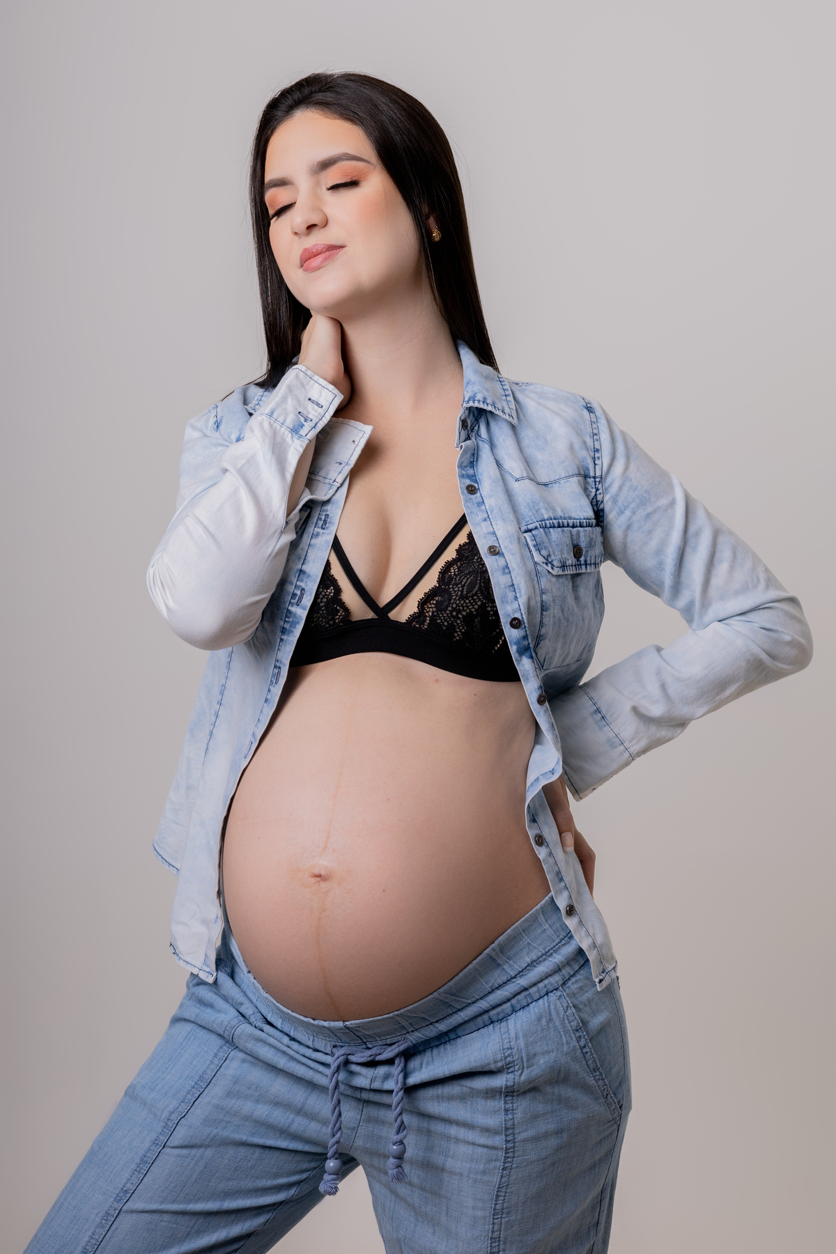 gestante com mão na cintura e outra no pescoço