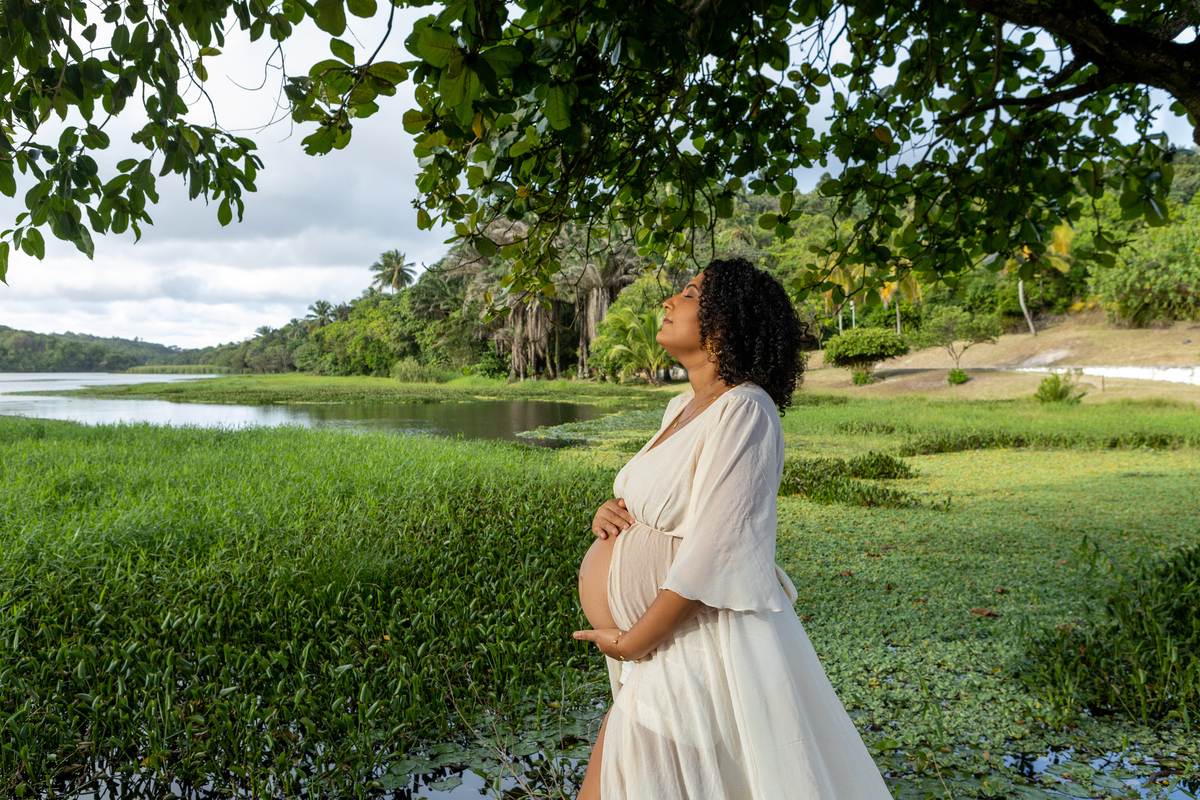 gestante abraçando a barriga no lago