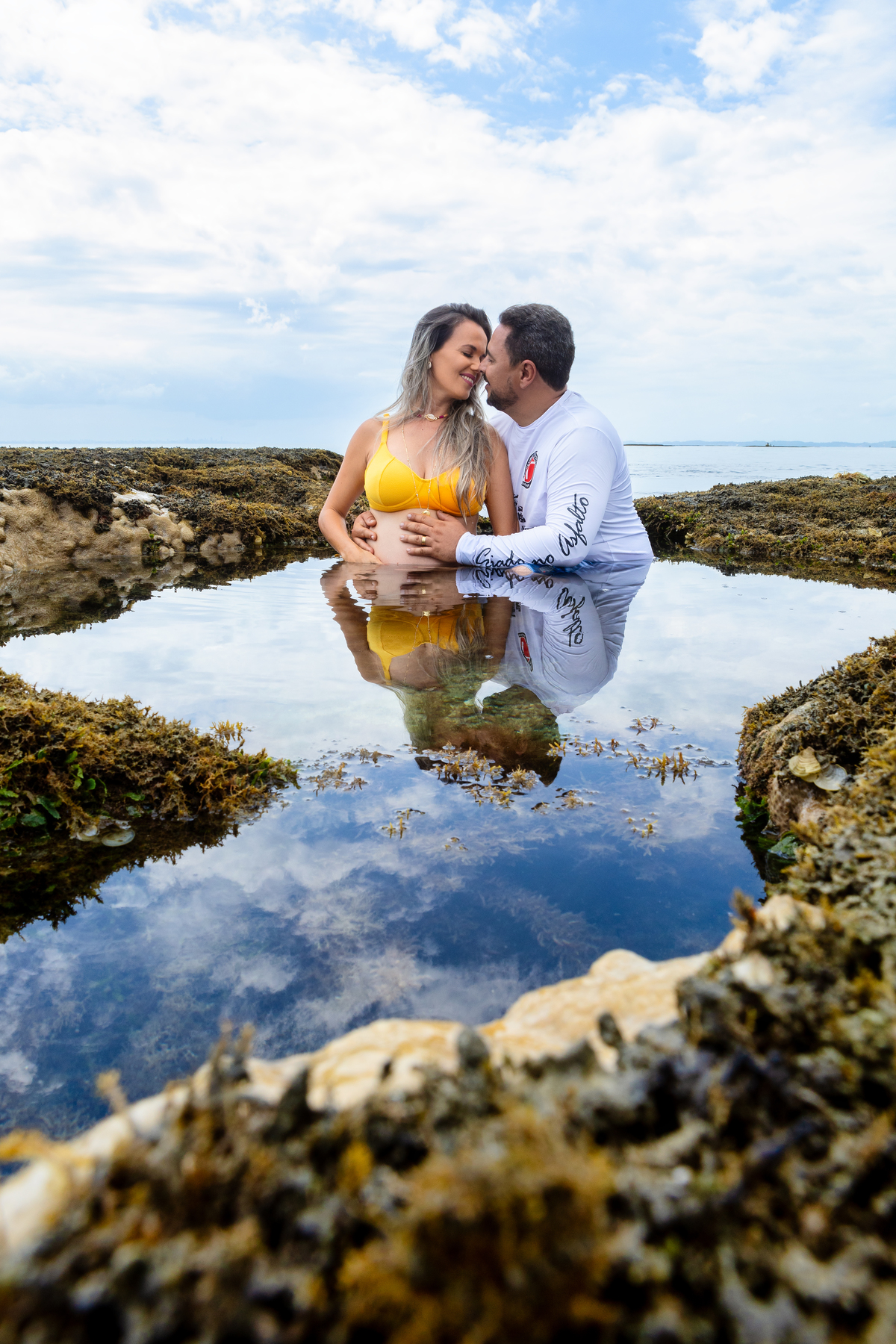 papai abraçando a barriga da gestante no mar