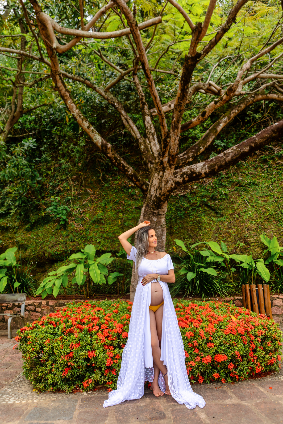 gestante encostada da árvore e tocando na barriga