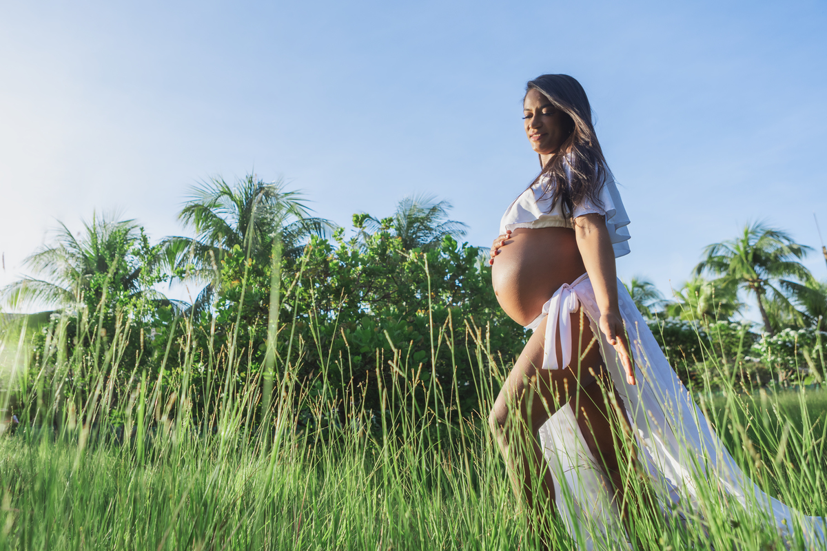 gestante andando pelo campo e tocando na barriga