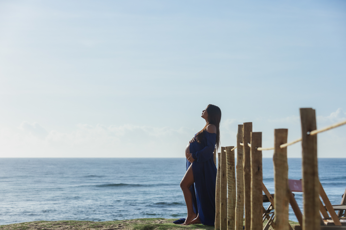 gestante abraçando a barriga na beira do mar