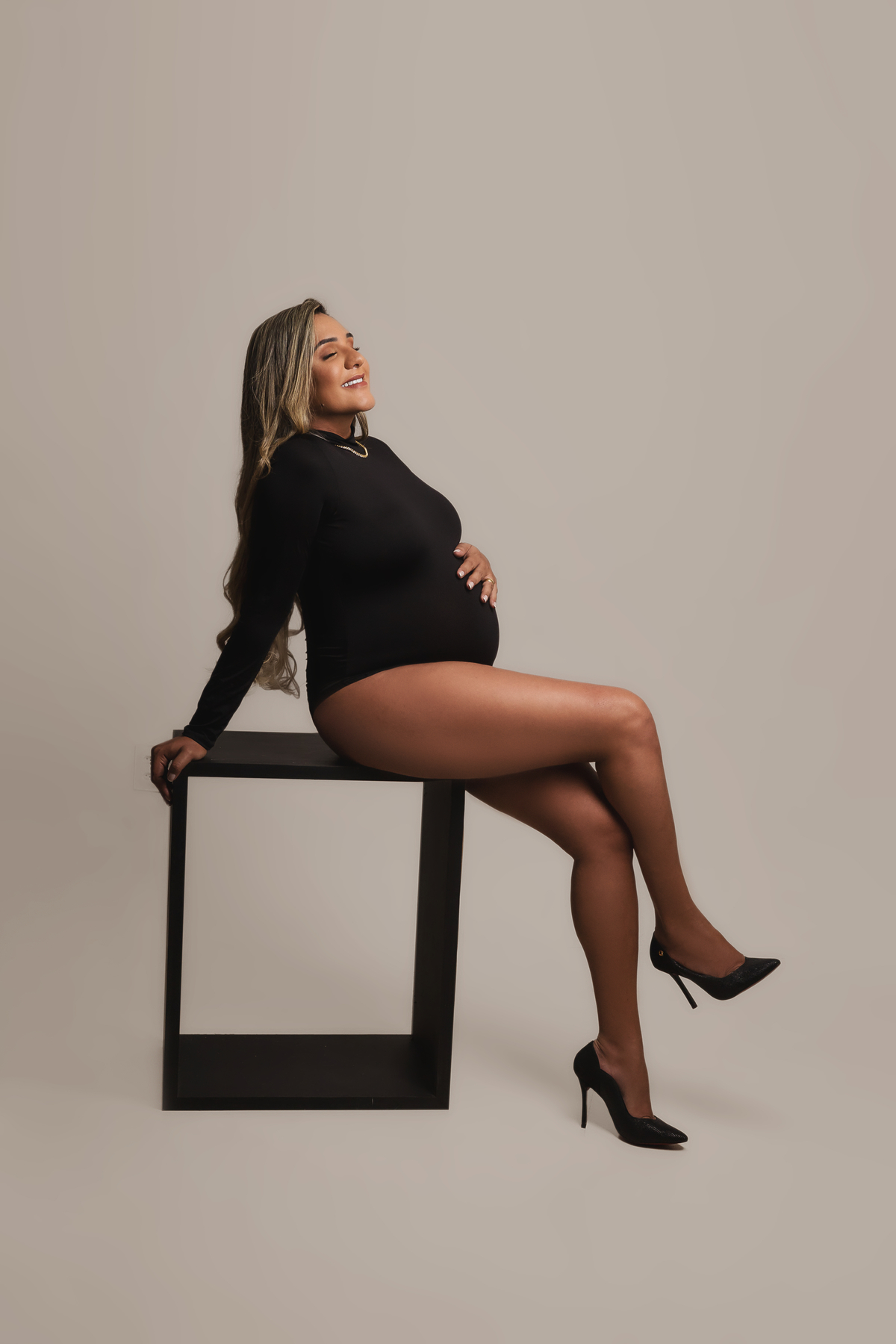 gestante sentada de perna cruzada e tocando a barriga