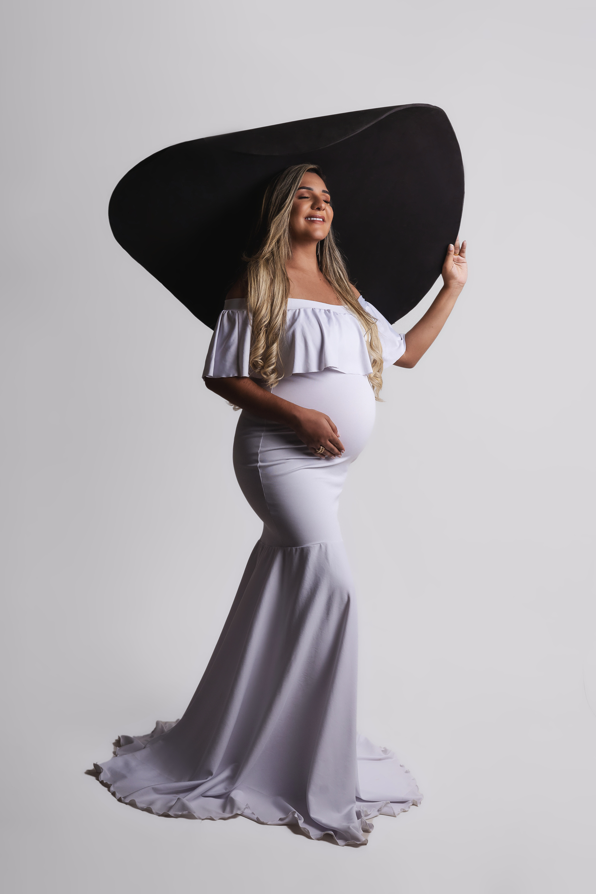 gestante segurando o chapéu e tocando na barriga