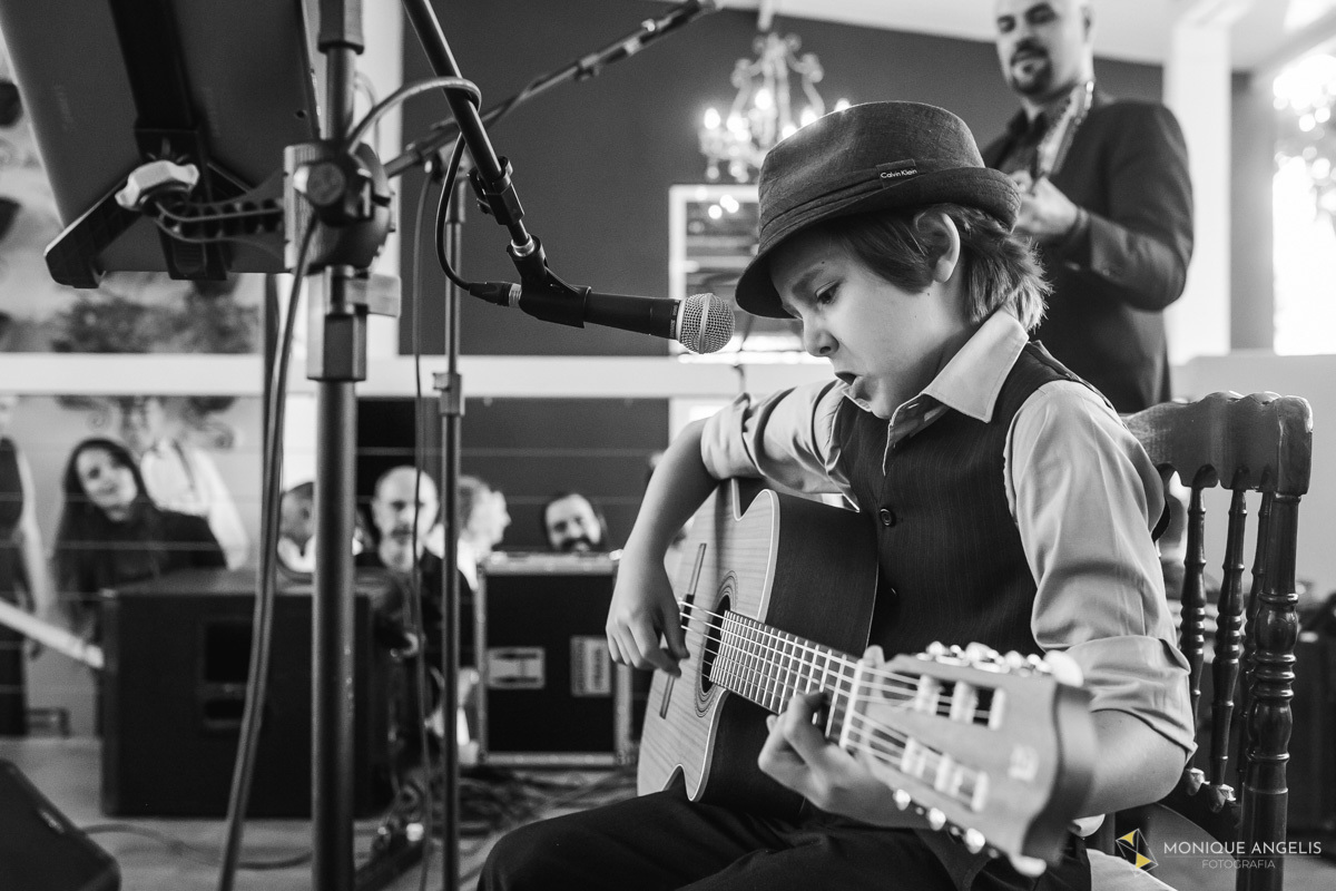 Menino tocando violão e cantando para os noivos na festa do casamento