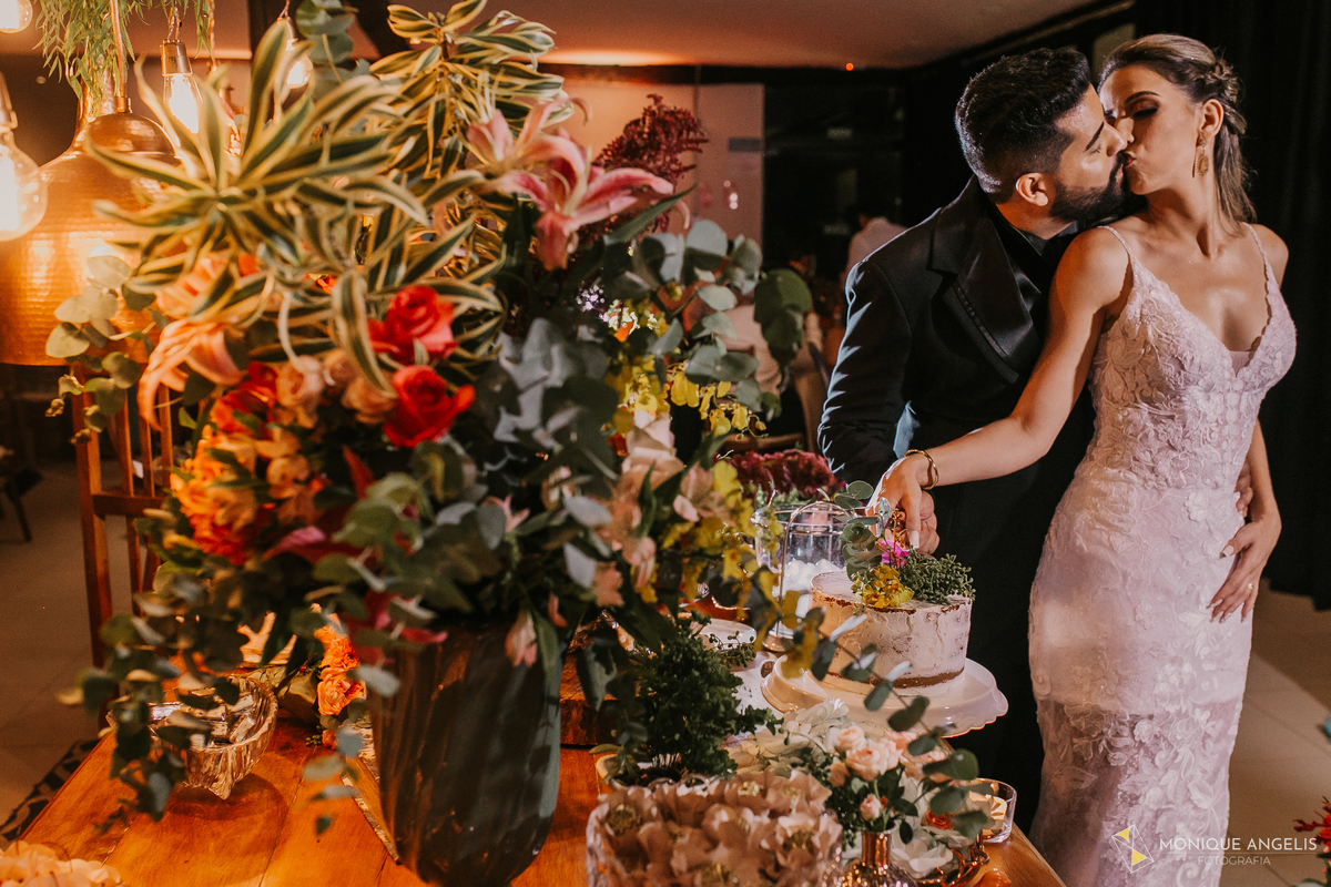 o beijo do casal de noivos durante o corte do bolo