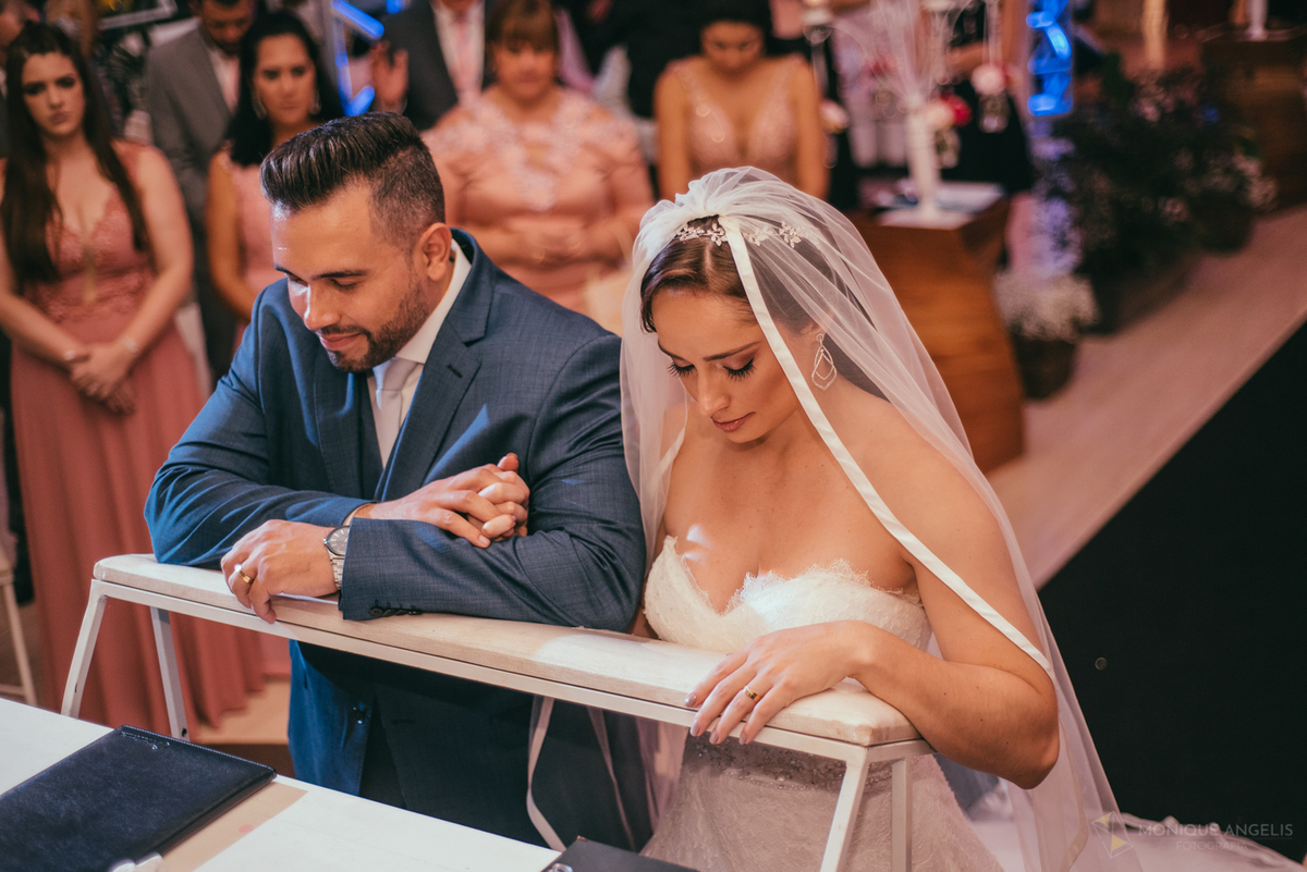 casal de noivos ajoelhados no altar