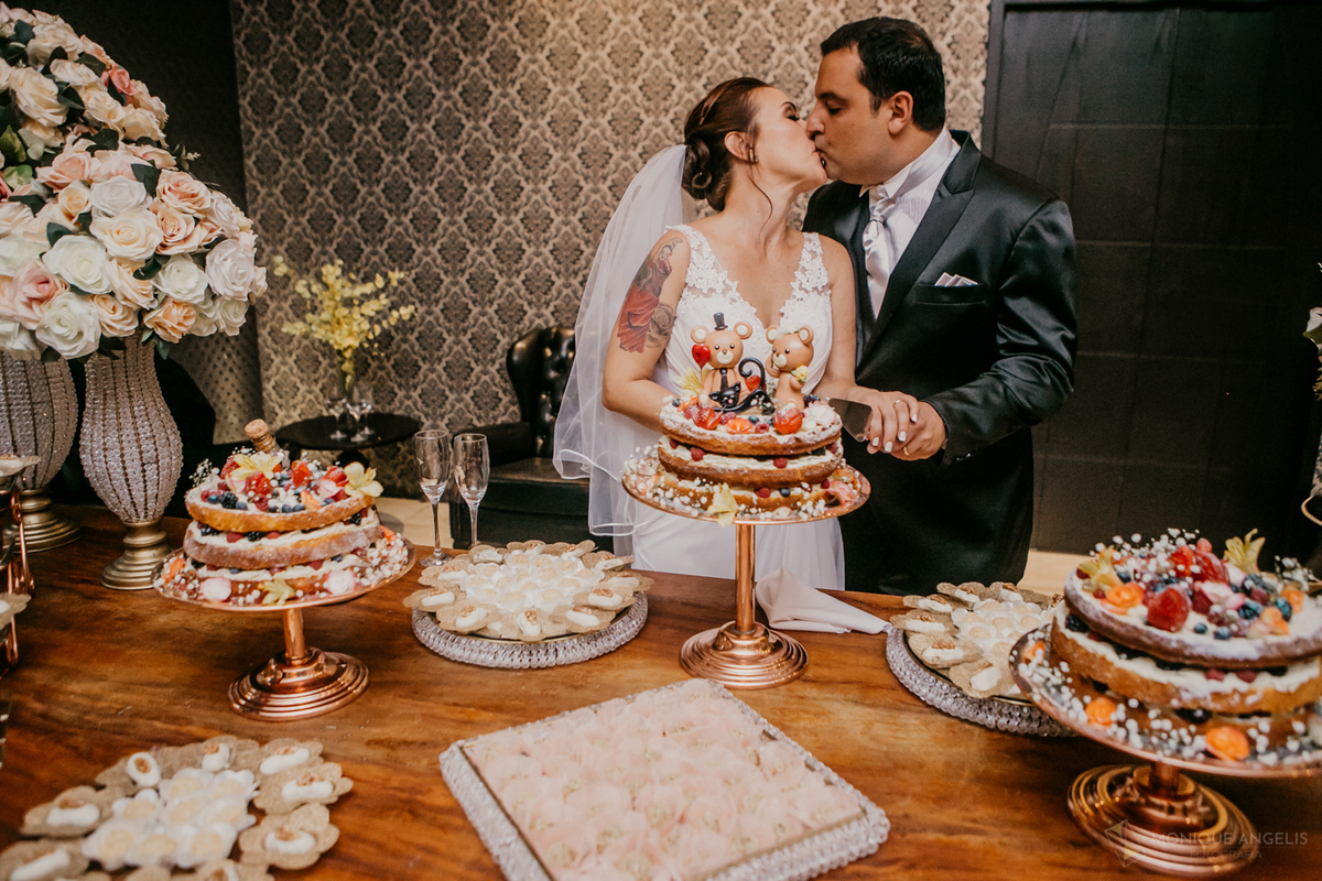 casal de noivos se beijando na mesa de bolo na Casa Bertolazzi