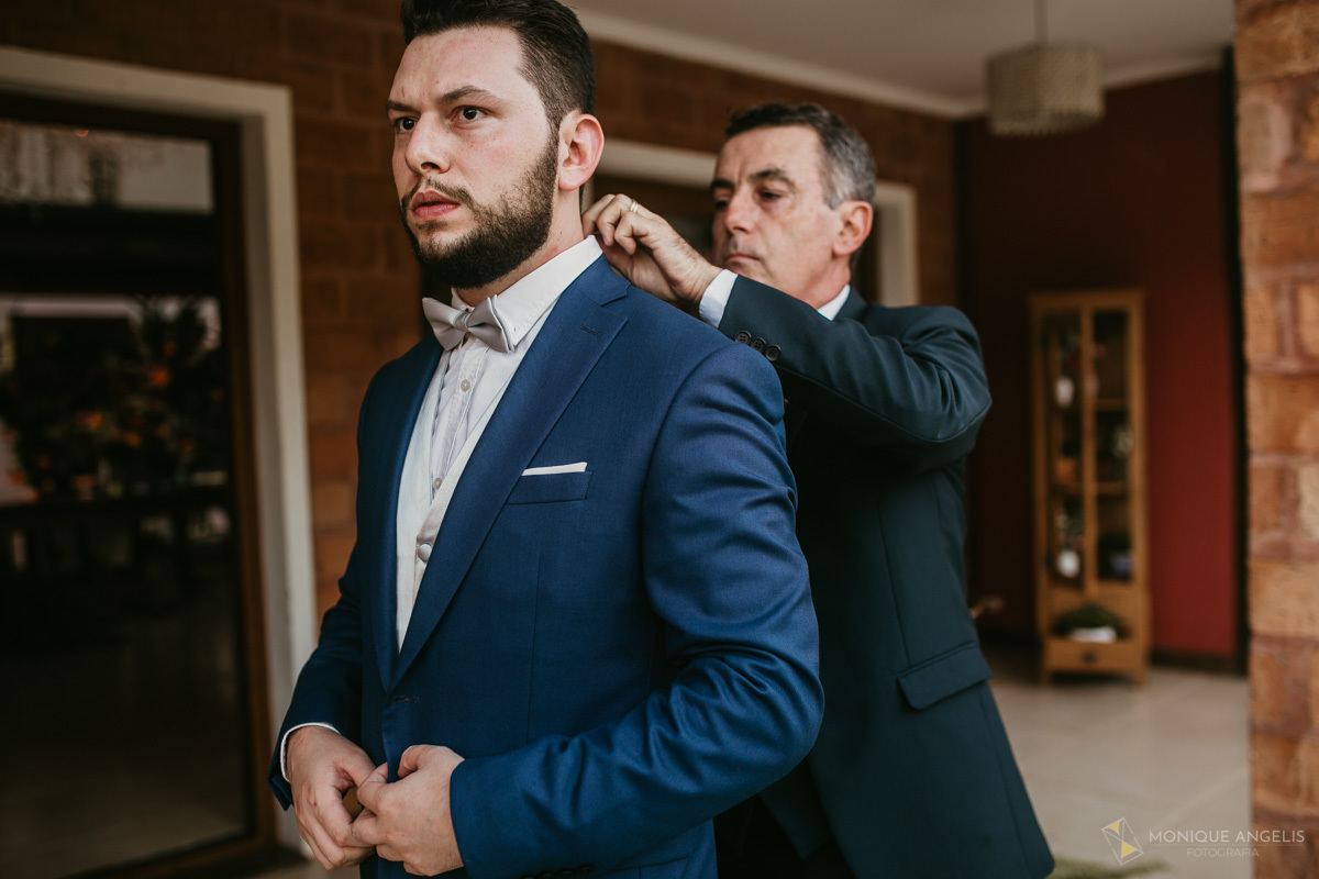 pai do noivo ajudando noivo a se arrumar antes do casamento