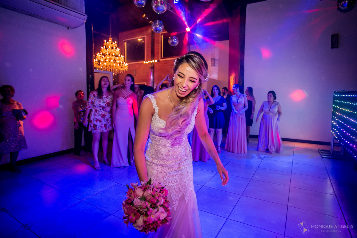 noiva brincando com o buquê antes de jogar para as solteiras na festa do casamento no Espaço Badulaque Eventos