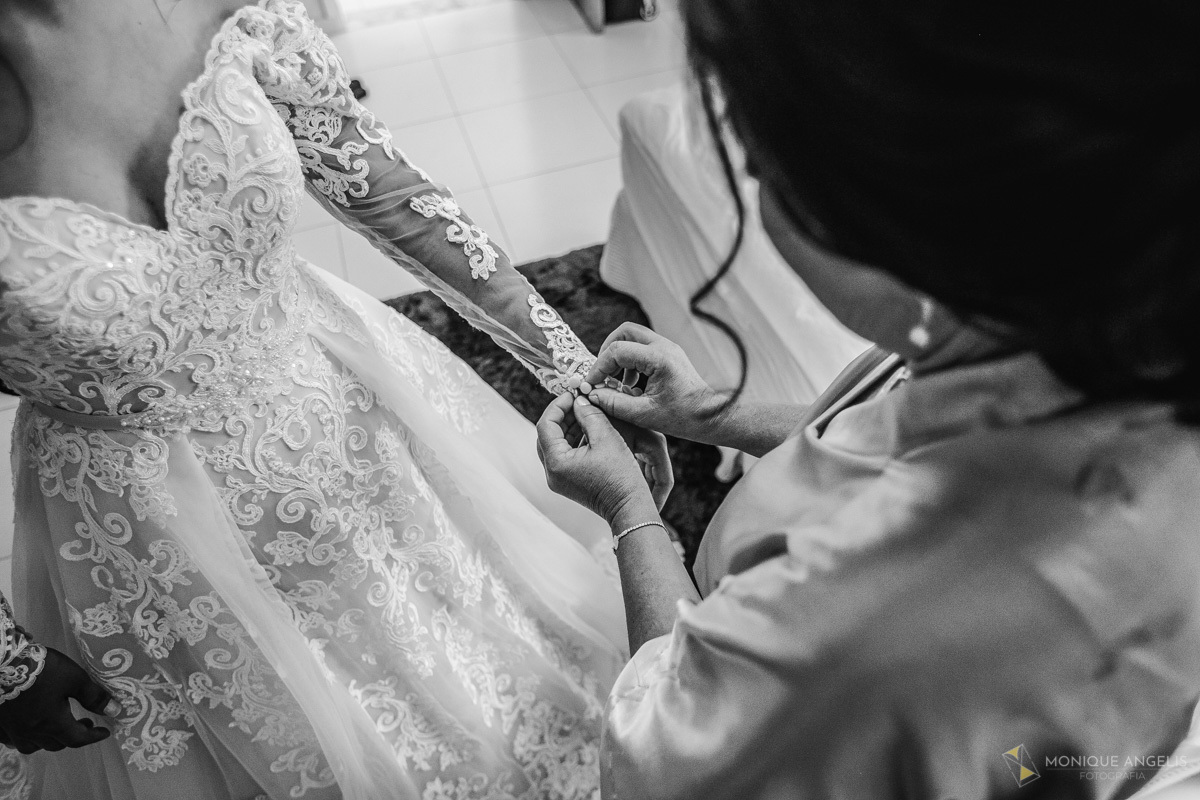 mãe da noiva ajudando sua filha a se vestir no making of da noiva