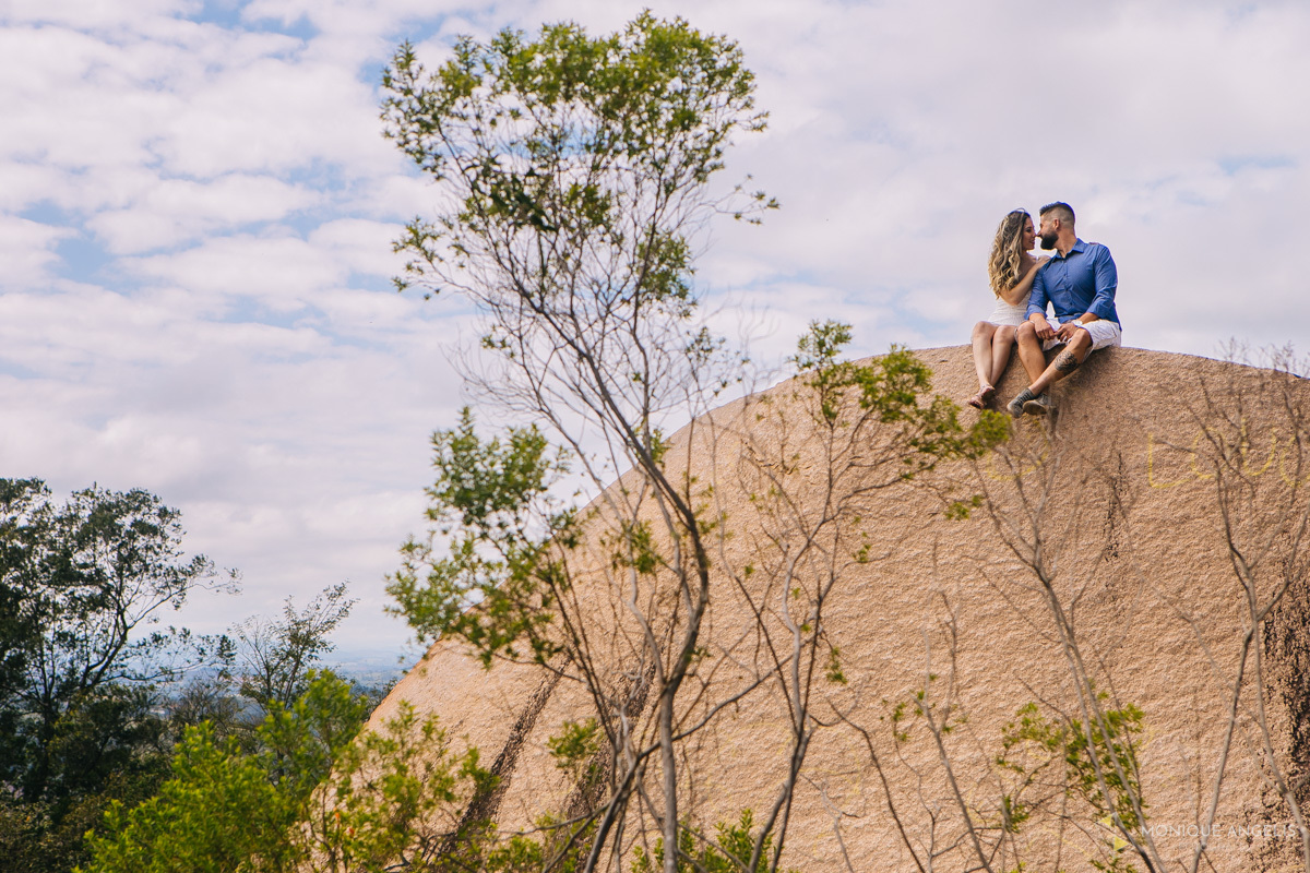 CASAL DE NOIVOS DE FRENTE A FRENTE SENTADOS NA PEDRA DURANTE ENSAIO PRE-WEDDING NO PICO DAS CABRAS
