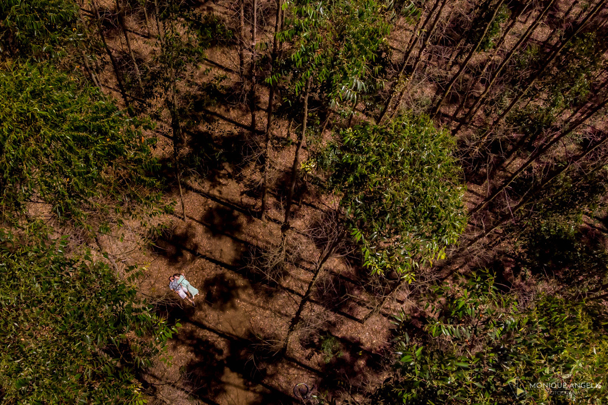 FOTO AEREA DE CASAL DE NOIVOS DEITADOS NO CHAO ENTRE ARVORES EM ENSAIO PRE-WEDDING EM JOAQUIM EGIDIO