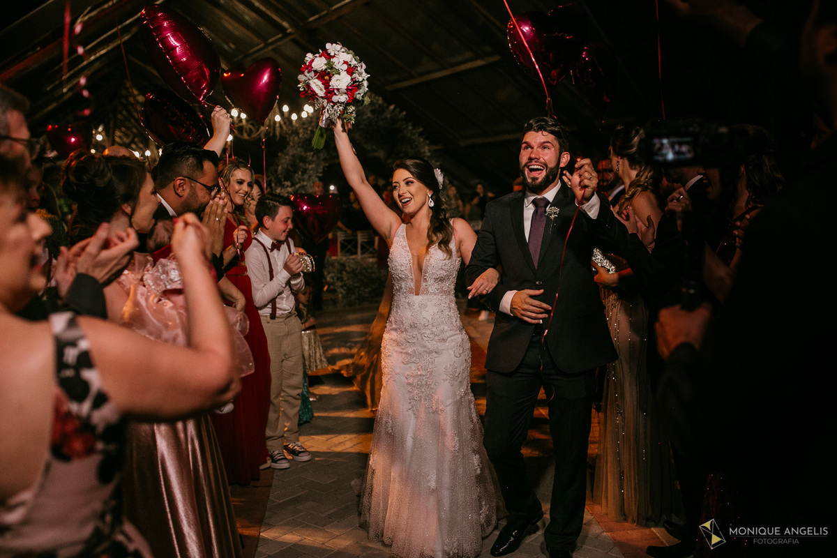 A saída do casal de noivos após o fim da cerimônia de casamento no Kratos Eventos