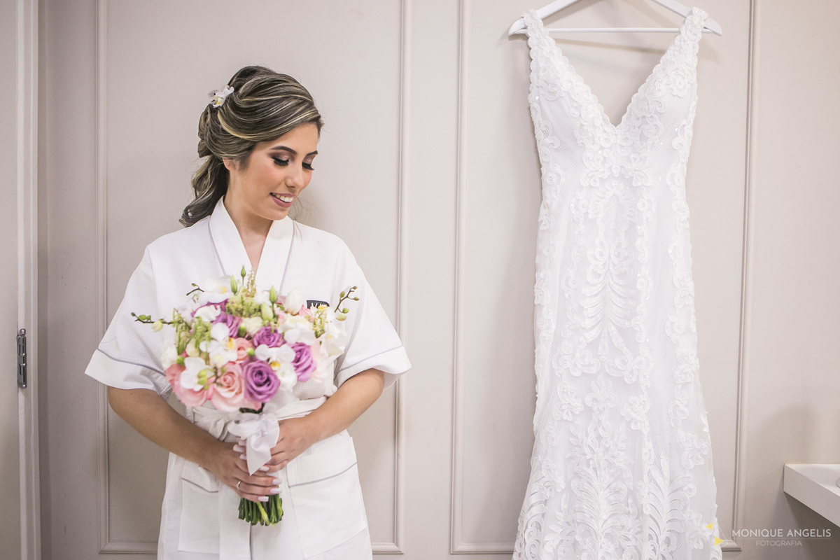 Noiva segurando o Buquê e admirando o Vestido durante o Making of no Agnaldo Cabelos