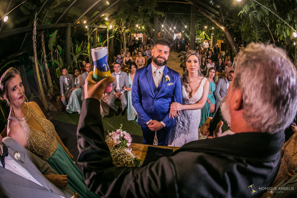 Celebrante de casamento apresenta o recipiente de areia ao casal de noivos e convidados do casamento na cerimônia de casamento no Restaurante Marupiara em Sousas SP 