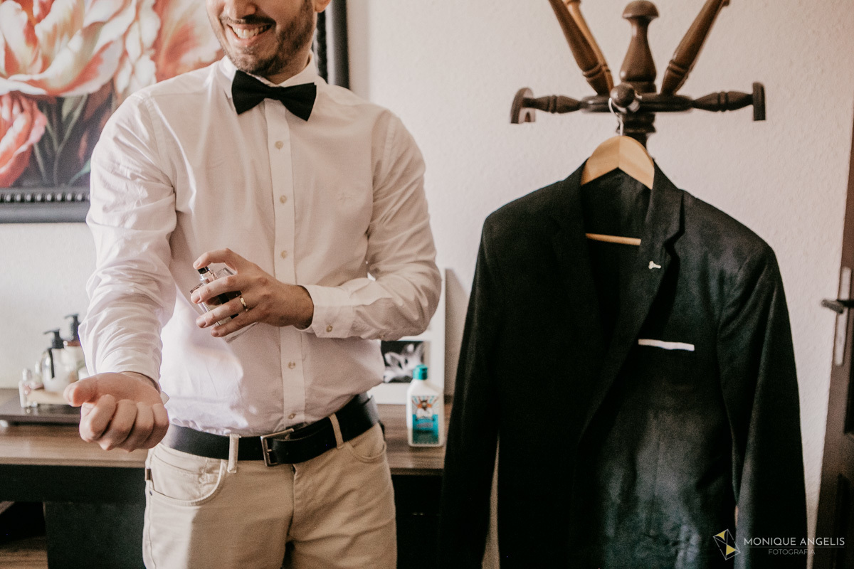 Noivo passando perfume em seu making of antes do casamento