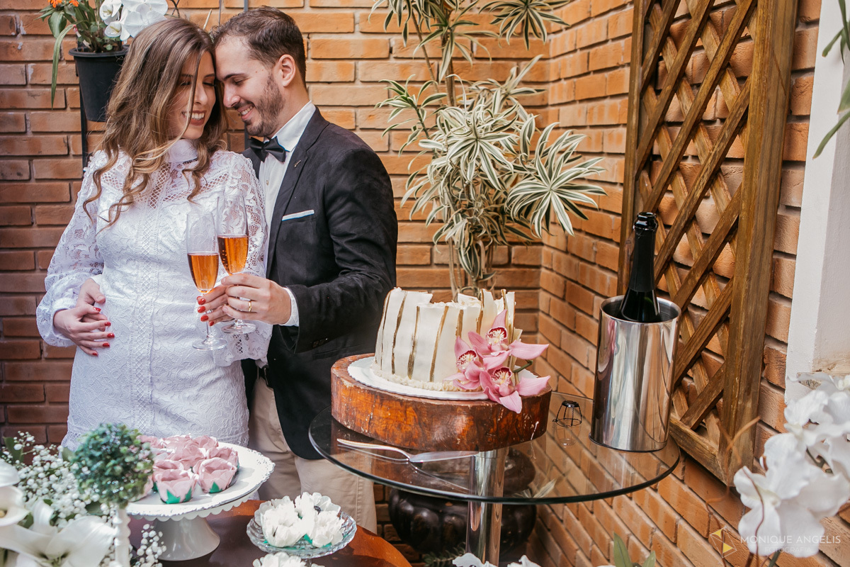 casal de noivos abraçados na mesa do bolo na recepção do casamento Civil em Valinhos SP