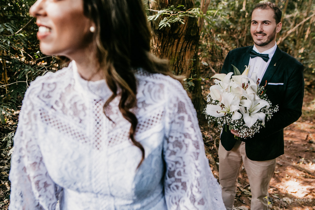 Noivo segurando o buquê e observando a noiva durante ensaio fotográfico após a cerimônia de casamento civil em Valinhos SP