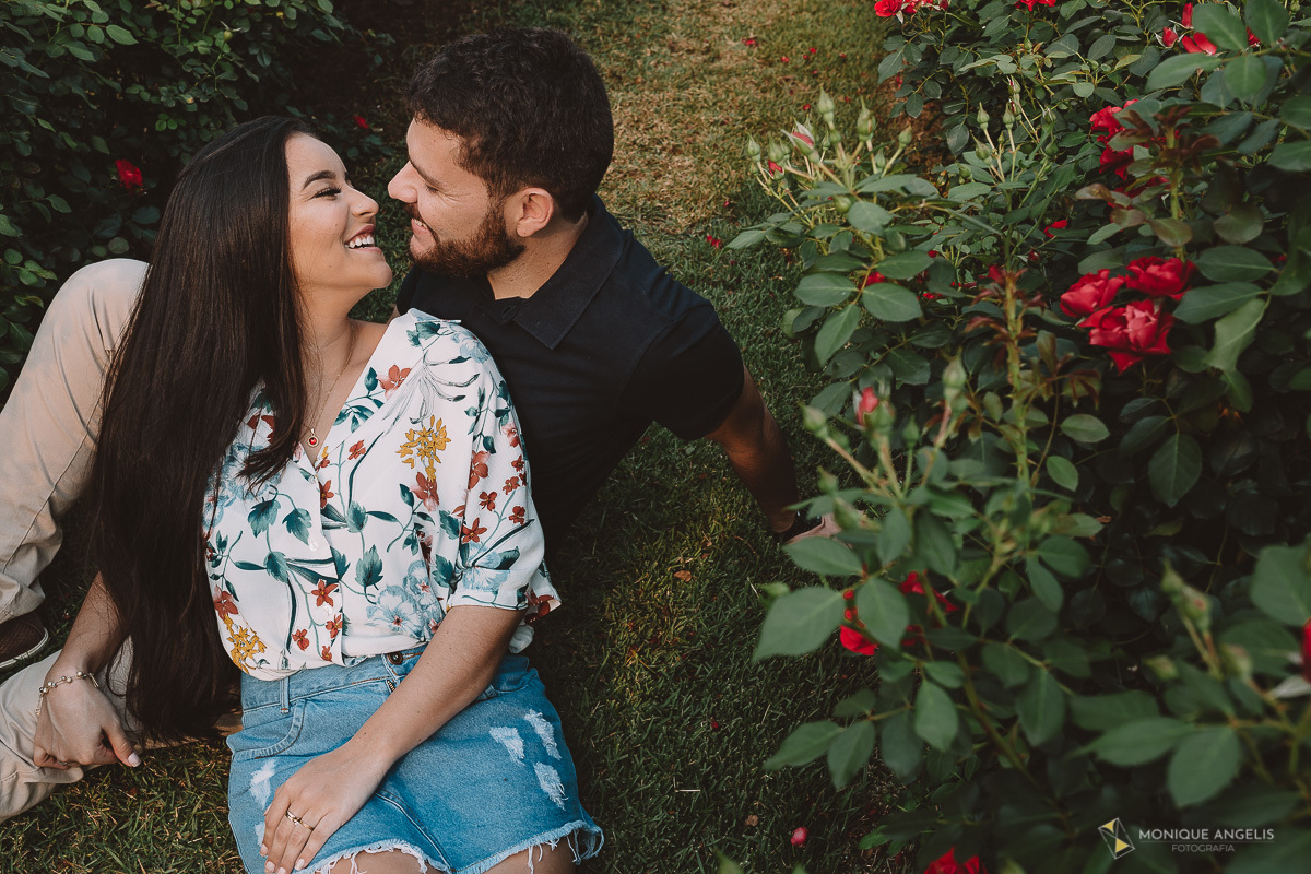 Casal de noivos sentados no chão entre roseiras se beijando - em Holambra SP - Por Monique Angelis