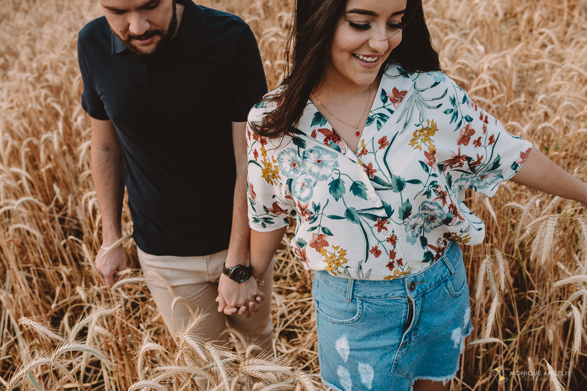 casal de noivos caminhando de mãos dadas entre trigo em Holambra SP - Por Monique Angelis