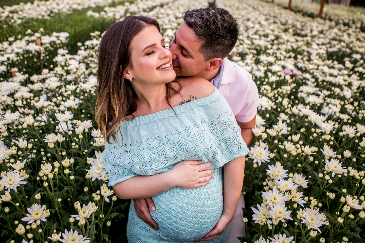 Casal Gestante se abraçando entre as flores