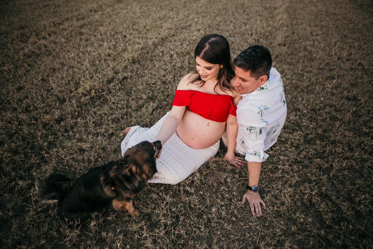 Ensaio Gestante - Casal gestante sentados na grama com cachorro de estimação