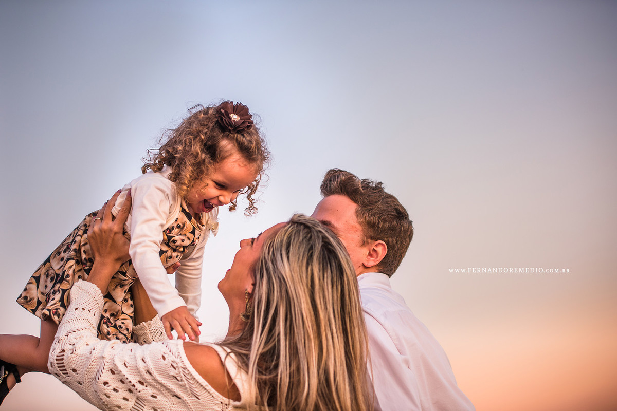 Foto ensaio familia com os pais brincando com sua filha laurinha posando para o fotografo em campinas